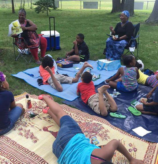 kids at camp sitting in blankets at the park