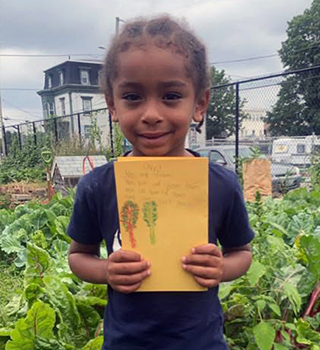 young child in front of garden holding drawing of garden african history for kids